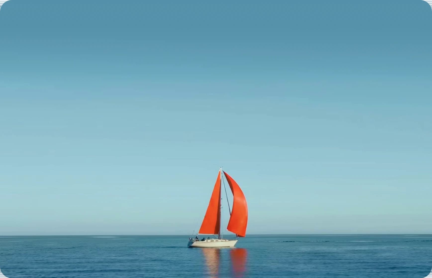 A sailboat with orange sails on open water